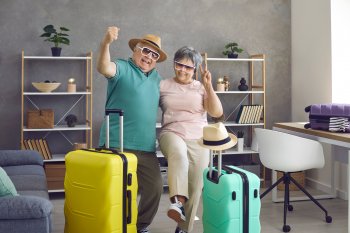 Gut gelauntes Ehepaar mit gepackten Koffern vor Reiseantritt