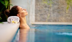 Eine junge Frau liegt entspannt in einem Außen-Spa-Schwimmbecken