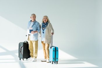 Glückliches Senioren-Paar mit Koffern, Reisdokumenten und Tickets