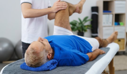 senior lässt sein knie beim therapeuten behandeln