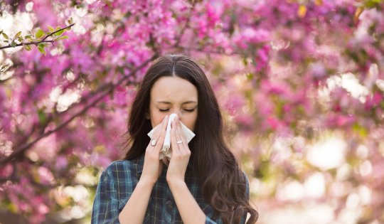 Woman blowing nose because of spring pollen allergy