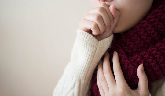 Young ill female have a cough and sore throat in winter. Causes of cough include common cold, flu, respiratory tract infection, pneumonia, bronchitis, allergy, asthma or COPD. Copy space. Health care.